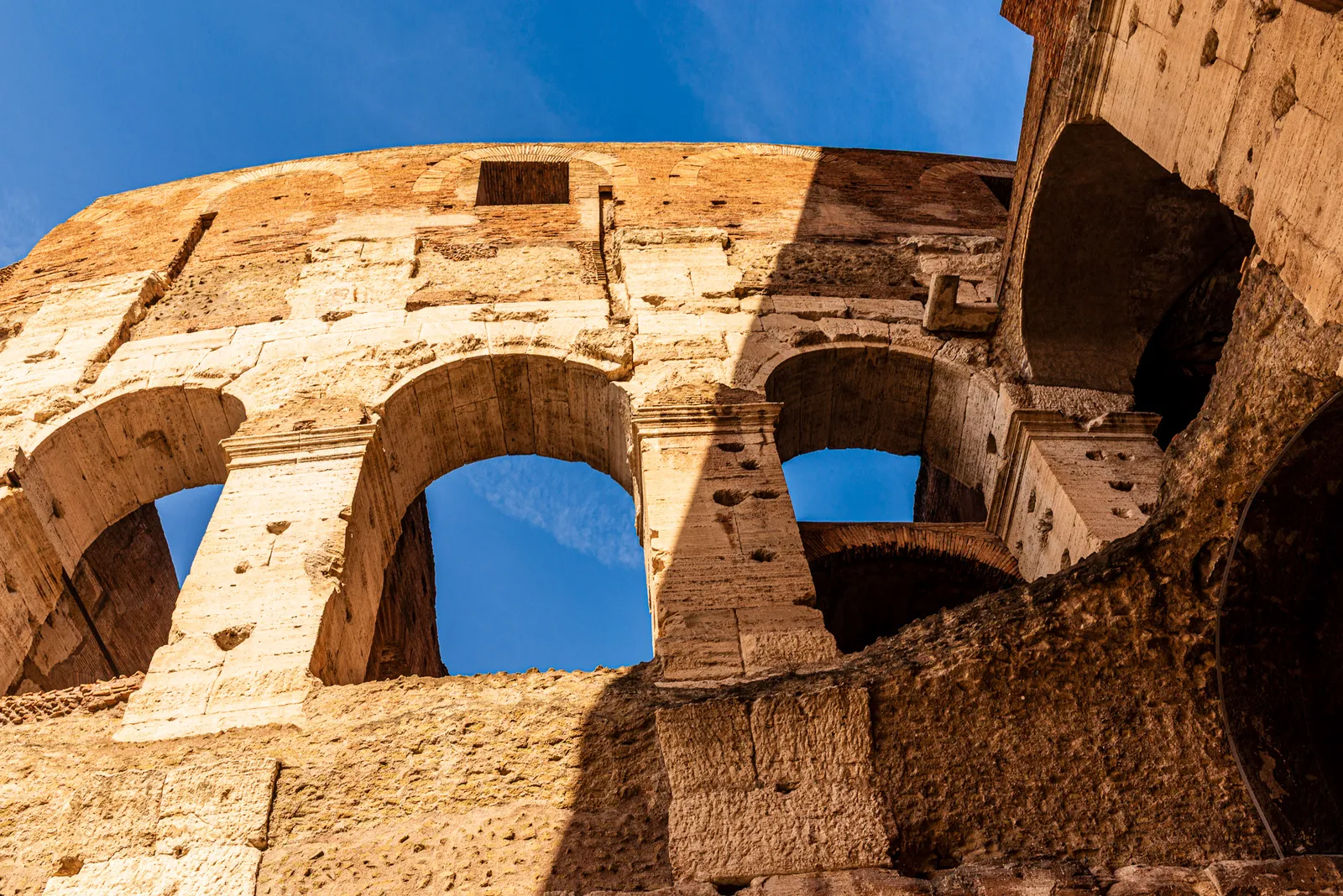 Warm afternoon sunlight striking the historic side arches of the Colosseum